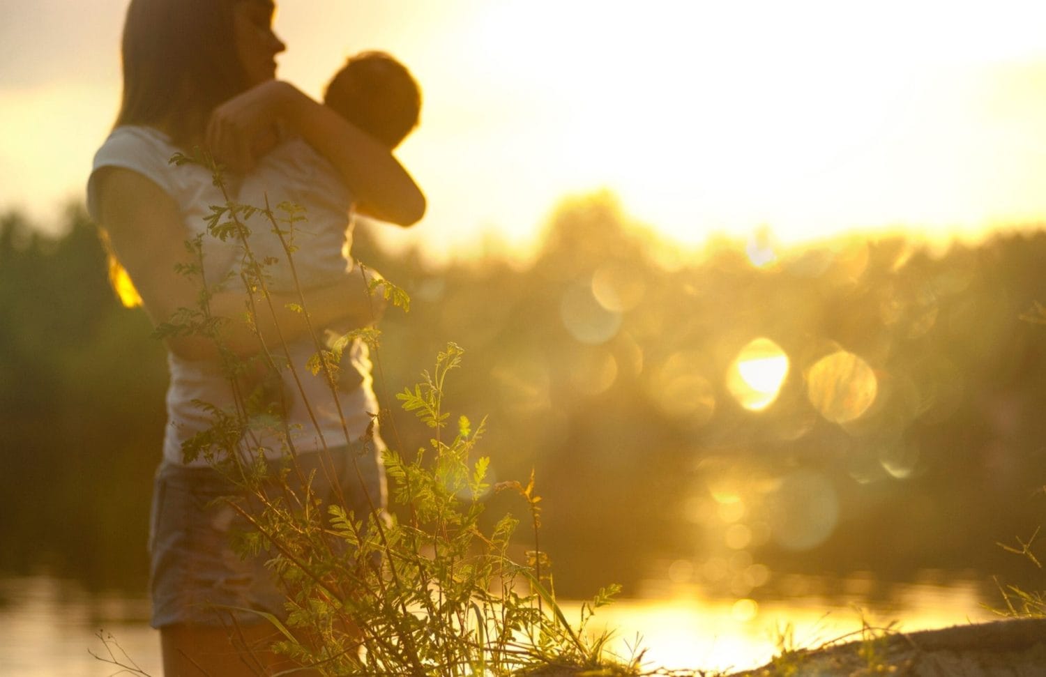 Self care ideas for mums: A mum carries her infant in the setting sun