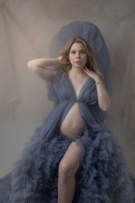 A woman poses for a maternity photoshoot in a creative portrait. A woman poses for a maternity photoshoot in a creative portrait.