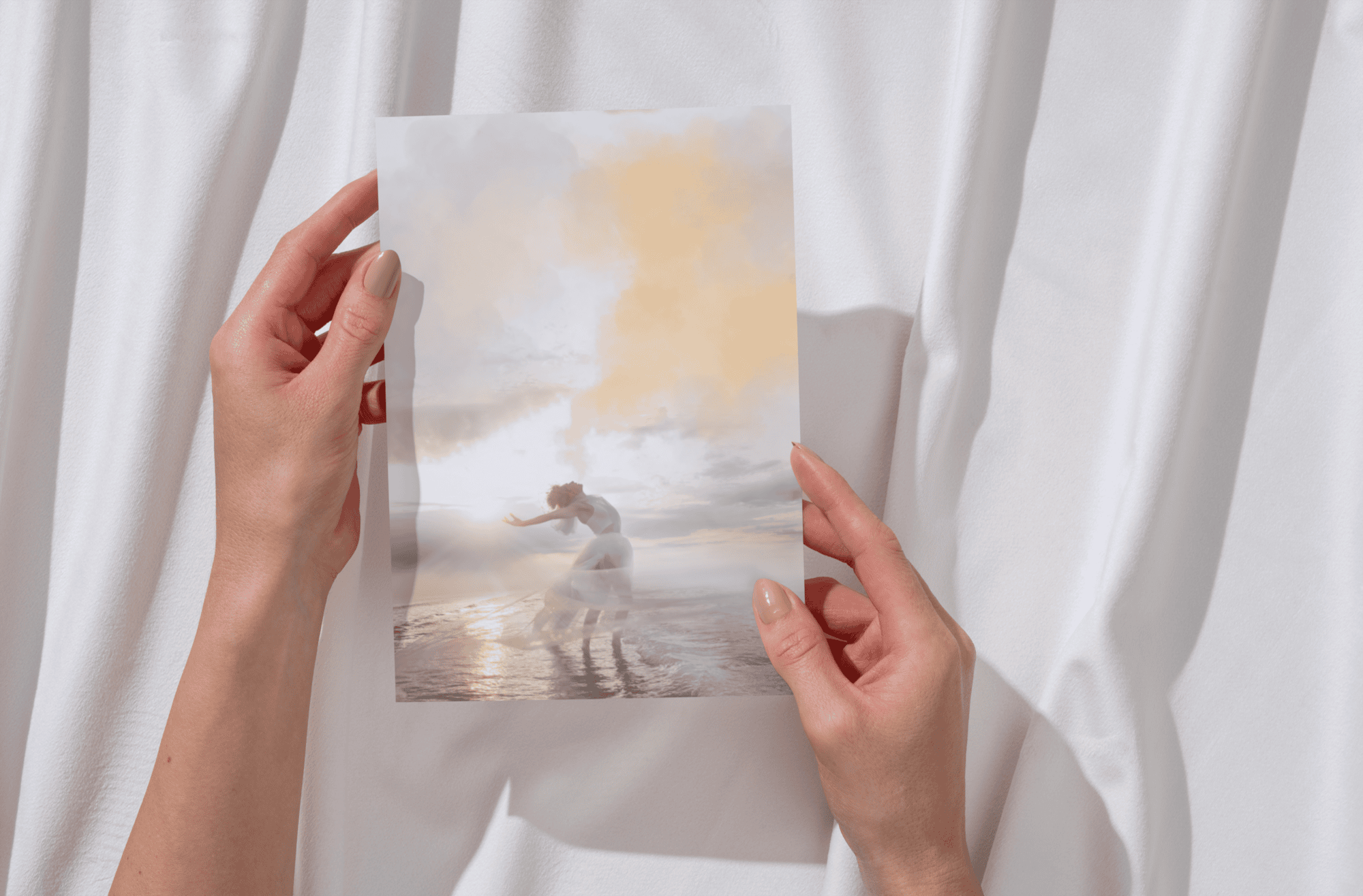Person holding a printed photo of a child at the beach with clouds in the sky.