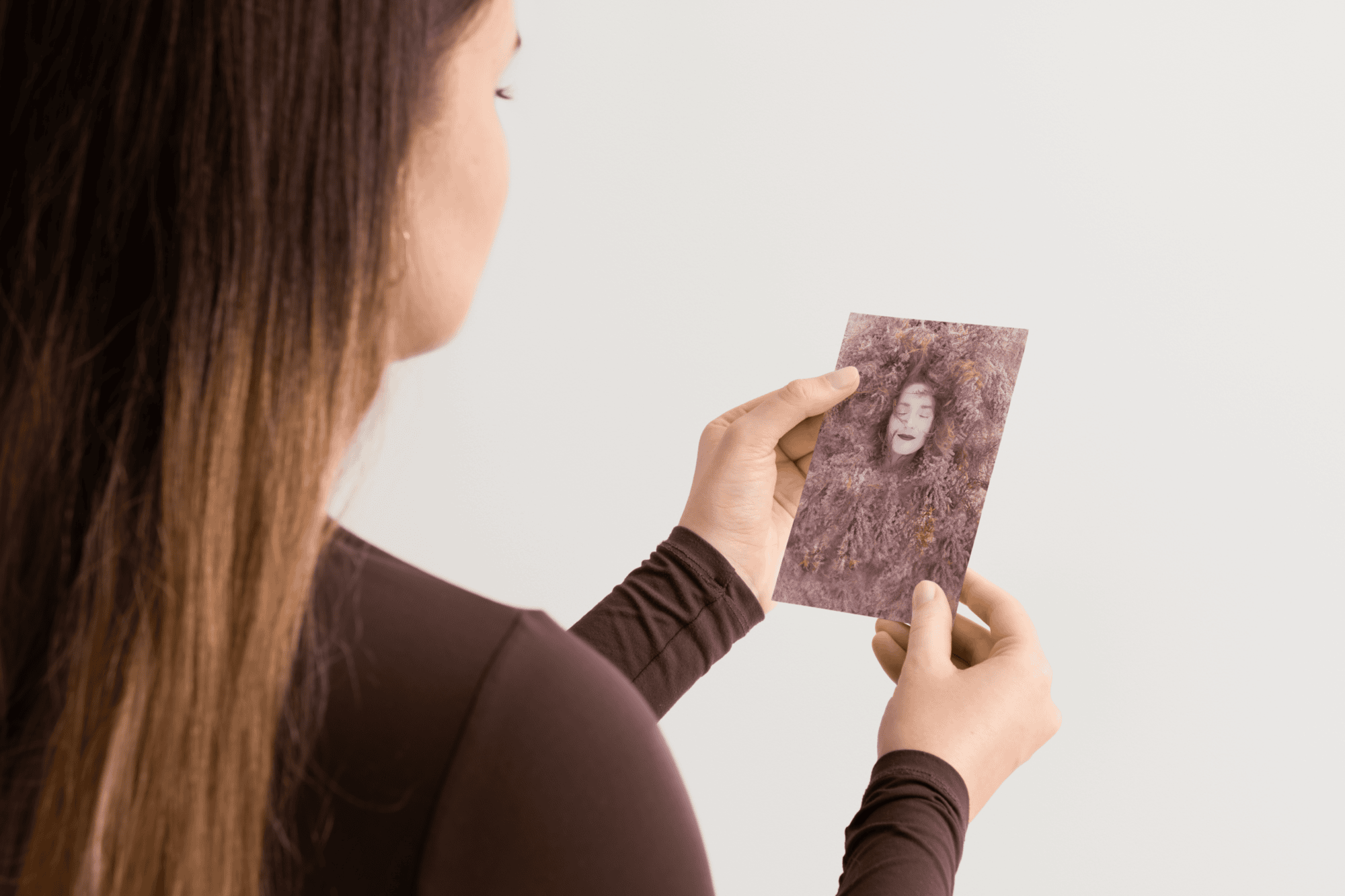 Woman holding a vintage-style portrait photograph with a plain background.