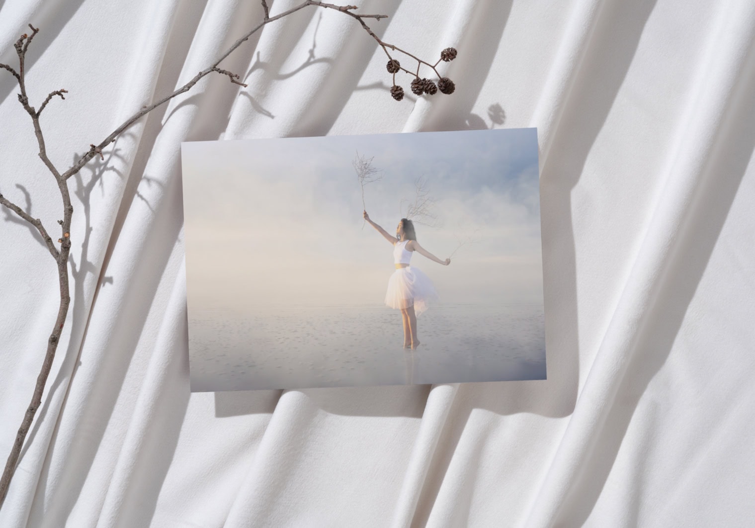 Artistic photo of a woman holding a branch with berries on a foggy beach.