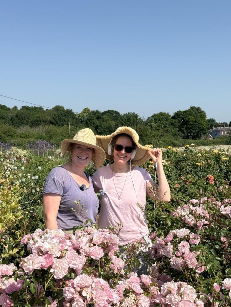Clare Redman, Gingerly Green Flower Farm, talks to Louisa Peacock on Where We Come Alive Two women in sun hats smiling in a colorful flower garden.