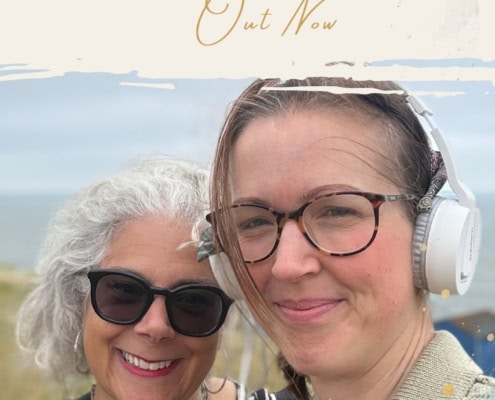Two women smiling outdoors, one with headphones, in a scenic natural setting.
