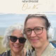 Two women smiling outdoors, one with headphones, in a scenic natural setting.